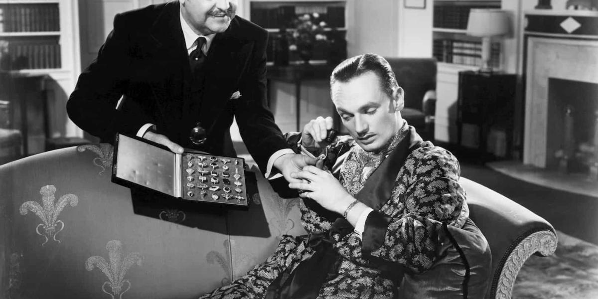 Old photo of a men presenting rings to another man for examination