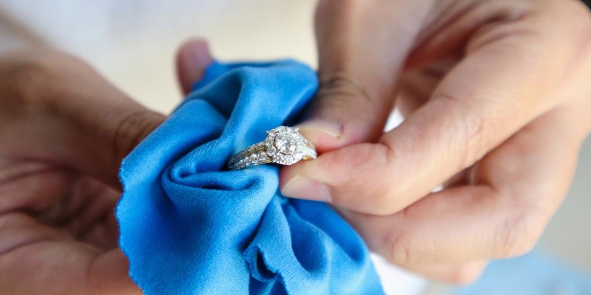 A jeweler is hand polishing and cleaning a diamond ring.