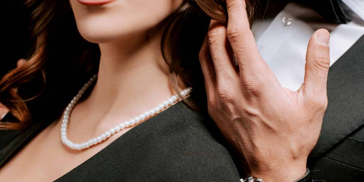 Picture of a woman wearing a pearl necklace and a man wearing a watch