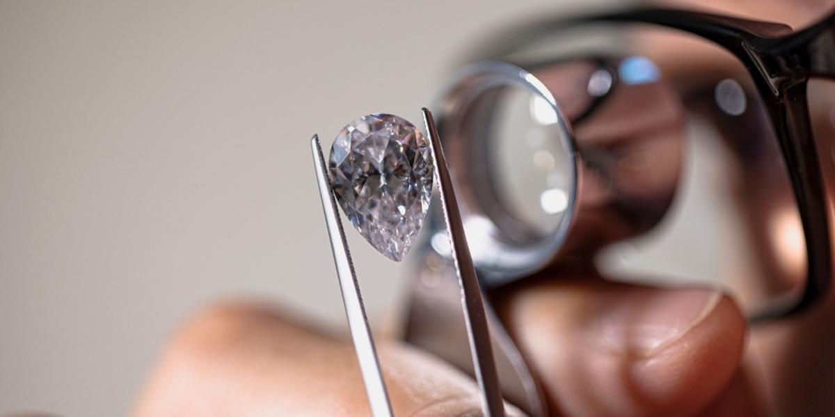 A jeweller is examining a diamond through a loop.