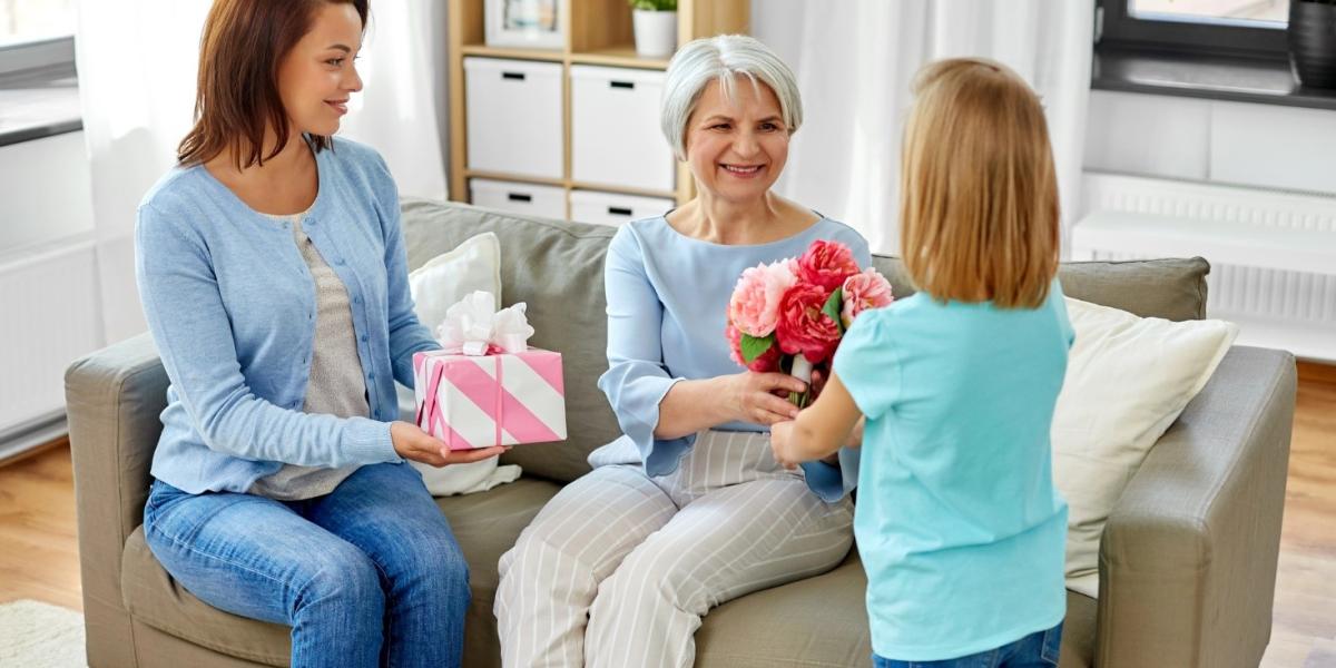 Granddaughter gives flowers to the grandmother, celebrating Mother’s Day.
