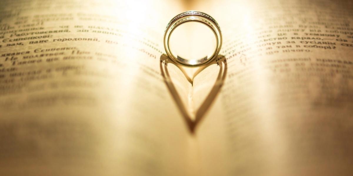 A ring casting a heart-shaped shadow on the pages of a book